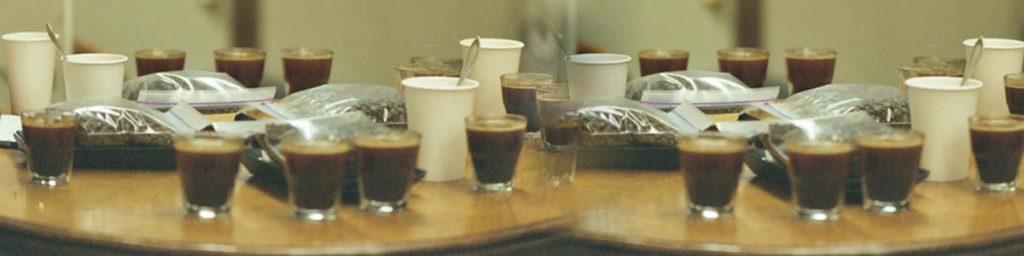 A table covered in espresso shots and bags of roasted coffee beans